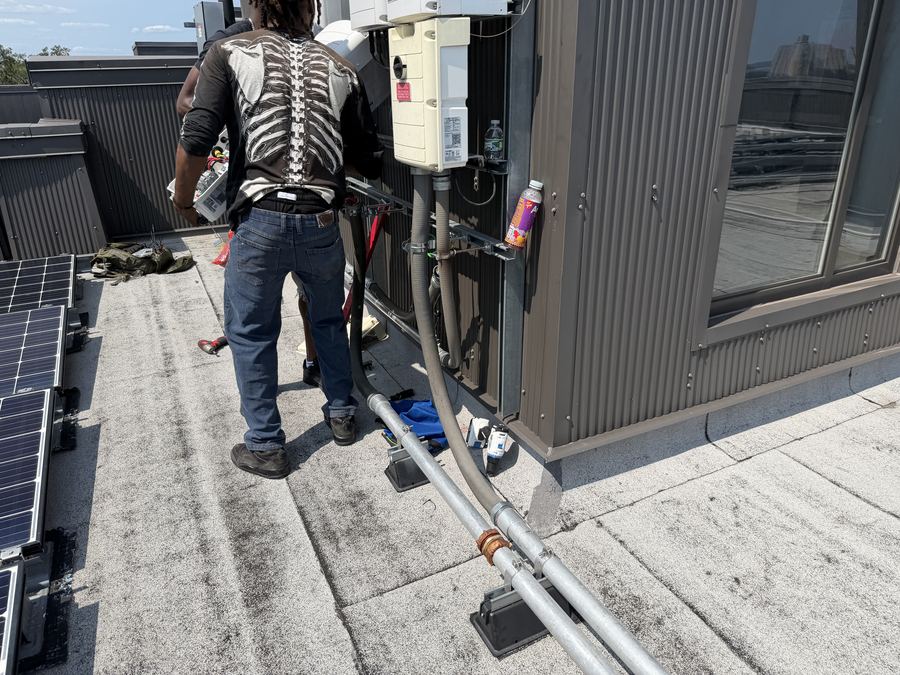 Technician working at a rooftop junction box on a commercial building with skyline visible