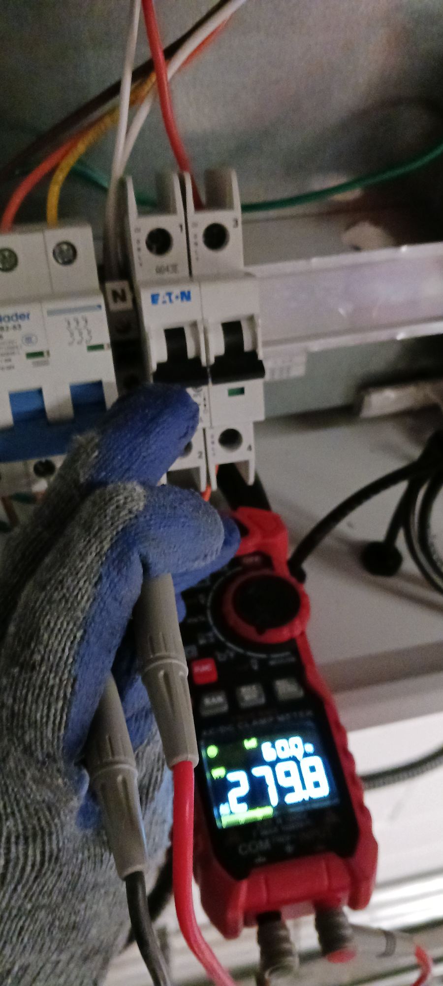 Clamp meter reading current at a breaker panel during a field assessment