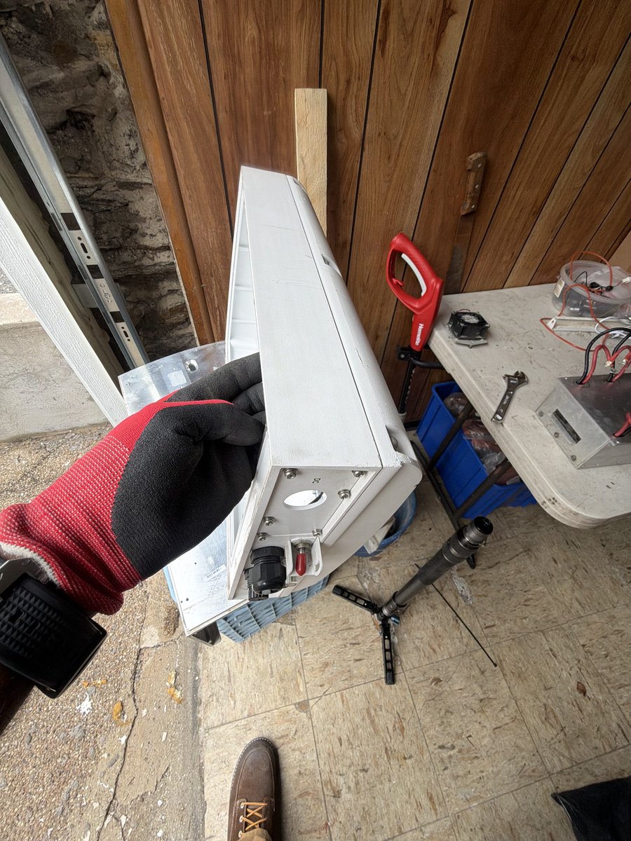 Technician removing a reusable enclosure assembly from a retired solar inverter